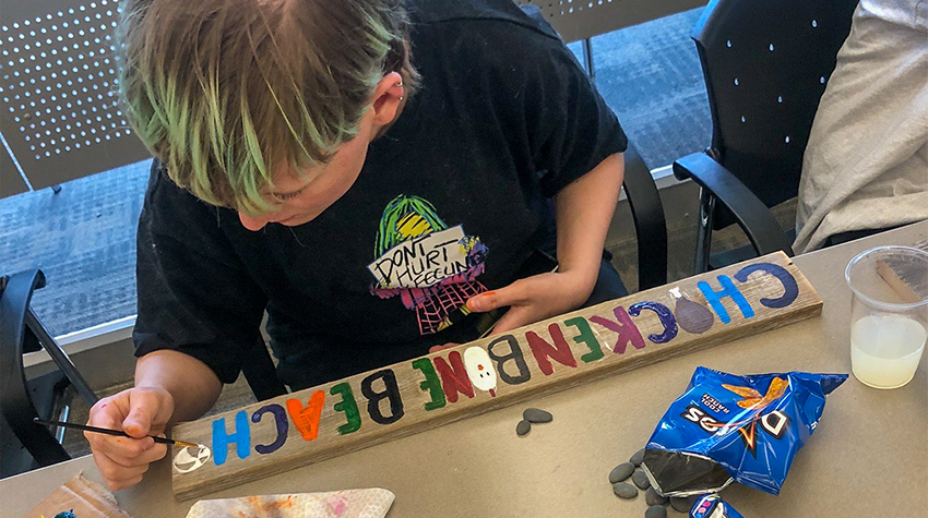 A student volunteer painting a sign for CBB