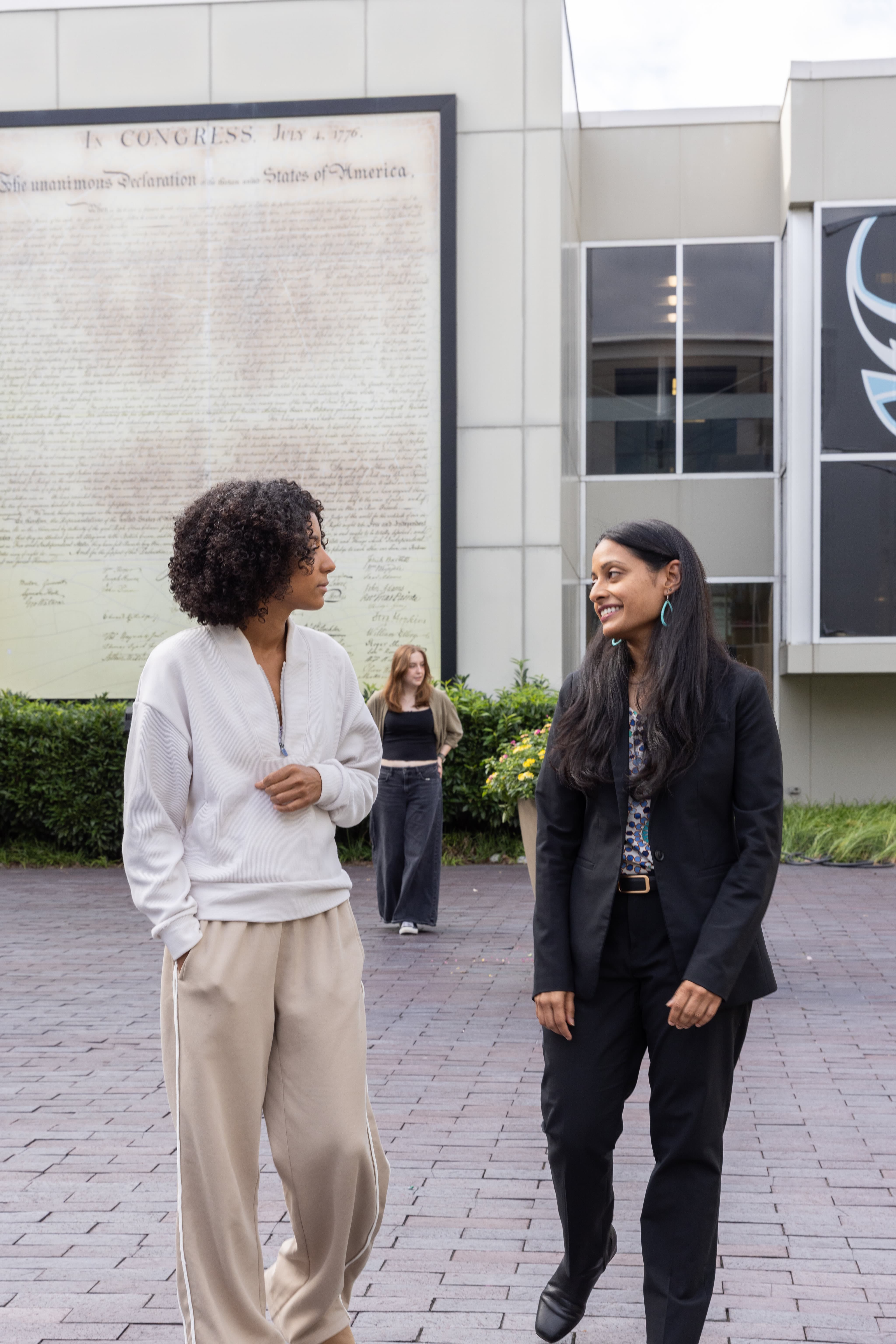 Keynote speaker Alina Das walks with a Stockton University student.