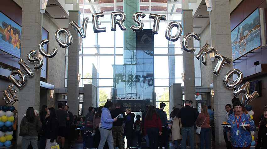 A crowd moving through the Campus Center under the #DiscoverStockton banner.