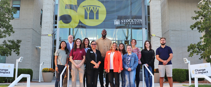 Michael Kidd-Gilchrist and Joe Donaher smile for the camera with students, staff and faculty in front of Stockton University's Campus Center on Oct. 15, before speaking on stuttering awareness and creating actionable change in the stuttering community.