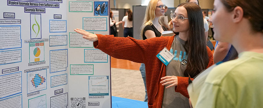 First-year Counseling graduate student Ashley Valentino, stands with her research at the spring Graduate Research Symposium in the Campus Center Event Room on April 29. More than 130 graduate students from 10 different graduate school programs presented their research at the event.