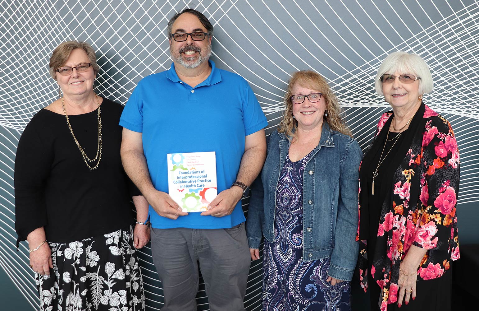 From left, Margaret Slusser, Luis Garcia, Patricia McGinnis and Carole-Rae Reed smile with their collaborative textbook, “Foundations of Interprofessional Collaborative Practice in Health Care.”