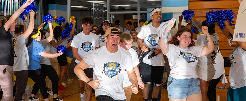 New Ospreys run into the I-Wing gym on the Galloway campus through a line of staff members cheering and welcoming them to Stockton during Residential Life's Summer Slam event.