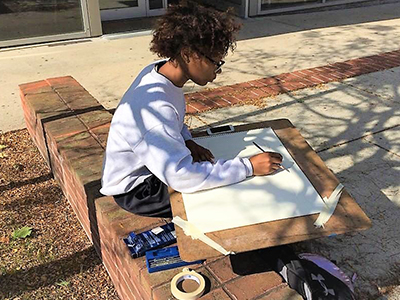 student drawing outside