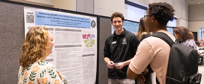 Brynna Mitchell and Jacob Ireland discuss their Occupational Therapy research project at the Scholarship, Teaching & Research Symposium opening breakfast on March 31. 