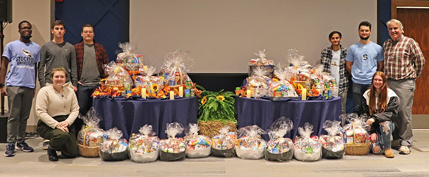 The Rev. John Scotland, executive director of the Friends of Jean Webster, with students and food baskets they collected for Sister Jean's Pantry.