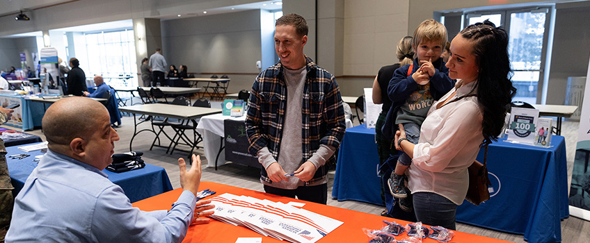 U.S. Coast Guard member Dallin Matthews, center, with his wife, Samantha, and their son, Raylan, talk with someone from Veterans Affairs during the Community and Veteran Wellness and Resource Fair on March 16.
