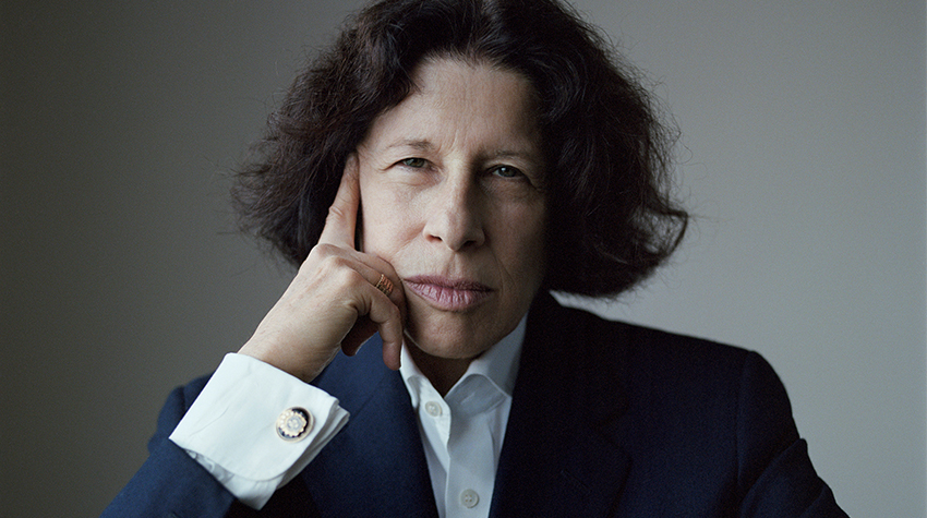 Fran Lebowitz, sitting with her arms crossed and her right hand on her temple