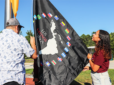 Britney Marrugo helping raise the Los Latinos Flag in A-Wing Circle