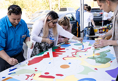 The community paints a mural at the Kramer Hall anniversary celebration.