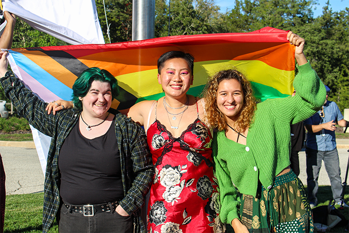 Pride Alliance president and members of QTPOCS under a rainbow flag