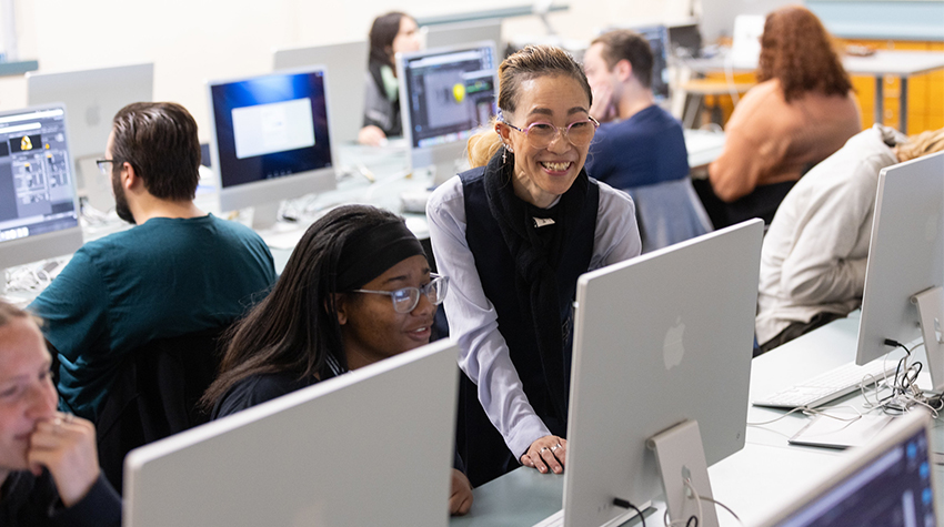 A professor helping a student on a Mac computer