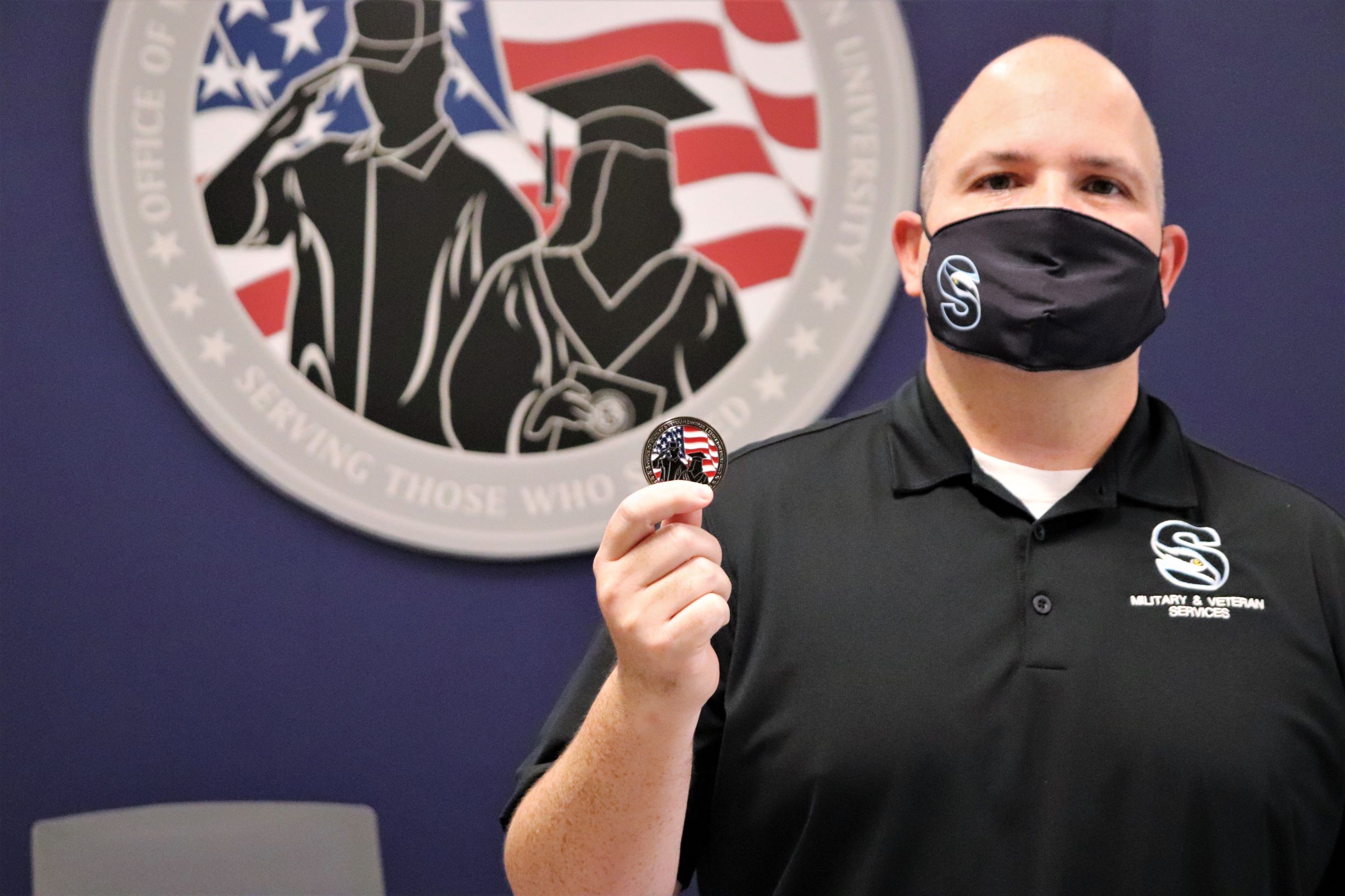 Director of the Office of Military and Veteran Services Jason Babin holds a Stockton challenge coin.