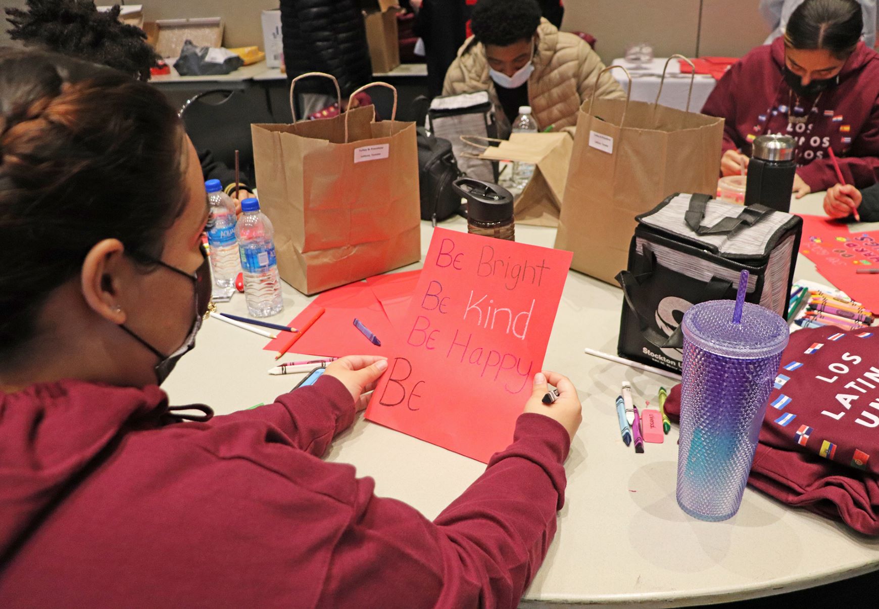 Senior Jazzlyne Muniz holds up a welcome back card she created for Atlantic City school children that reads, "Be Bright, Be Kind, Be Happy."