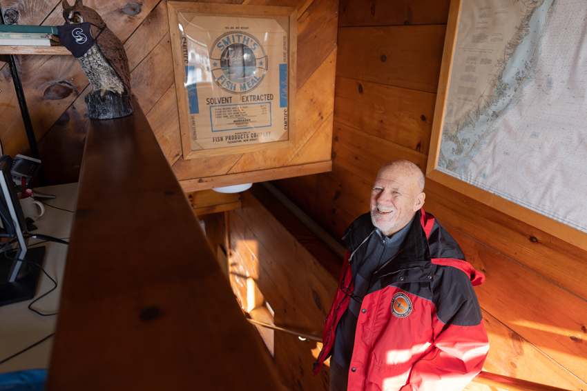 Stewart Farrell stands next to a framed bunker meal bag from the local Fish Factory