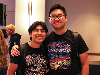 Pair of students smiling with their arms around each other's shoulders.