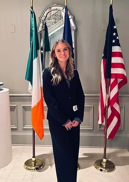 Giana standing in front of three flags in a government building