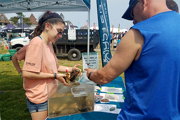 Image of Rebeka Seymour educates the public about the importance of oysters at a Jetty Rock Foundation outreach event. 