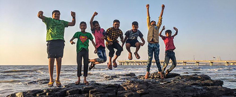 Elementary school students jumping near jetty