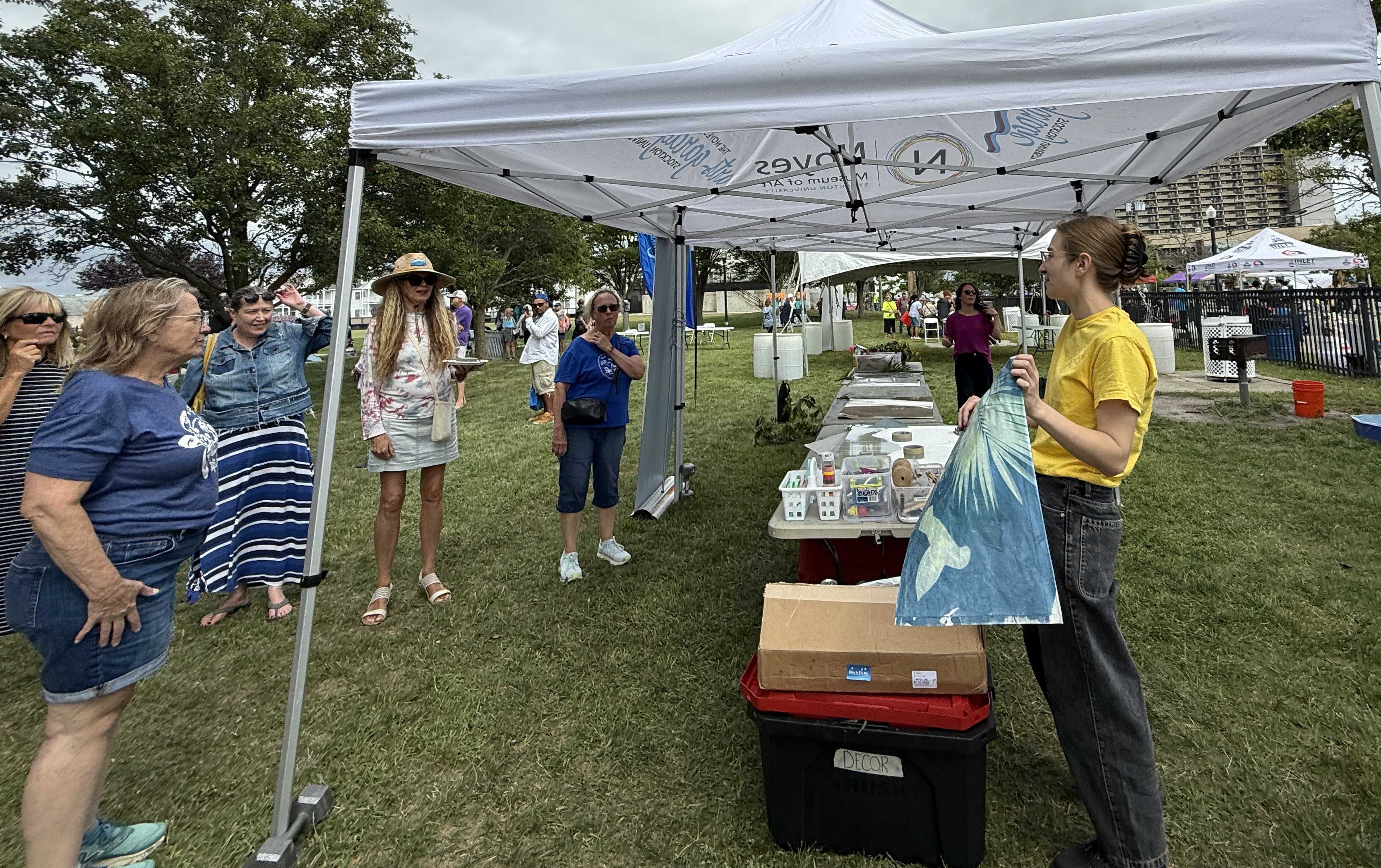 woman under vendor tent holding shirt 