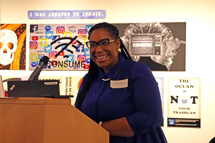Alexis Jenkins smiles as she stands behind a podium in the Art Gallery