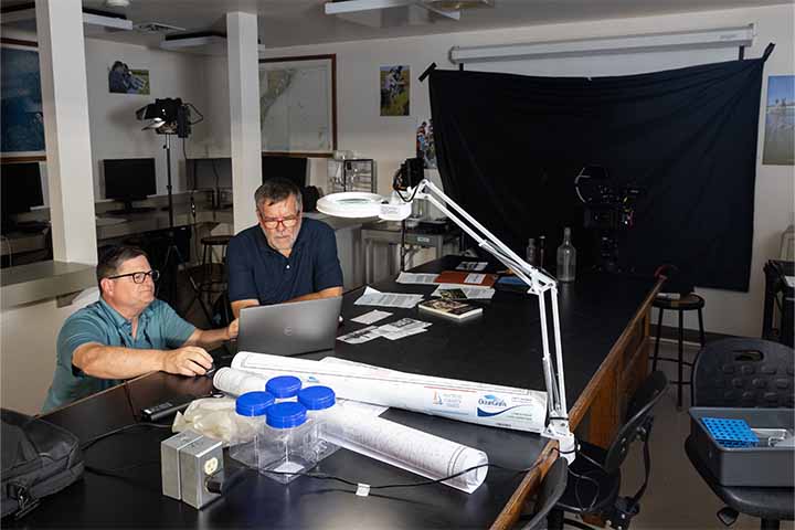 Two scientists at a large lab table examine a sample