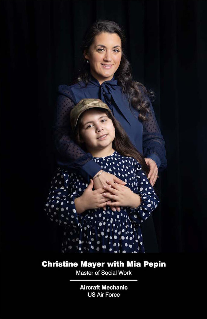 Christine Mayer in a blue button down shirt poses with her young daughter Mia Pepin in front of a black backdrop