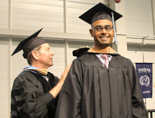 Amar Shah is congratulated on earning his MBA by Business Studies Professor Michael Busler at the Master’s and Doctoral Commencement held May 10.