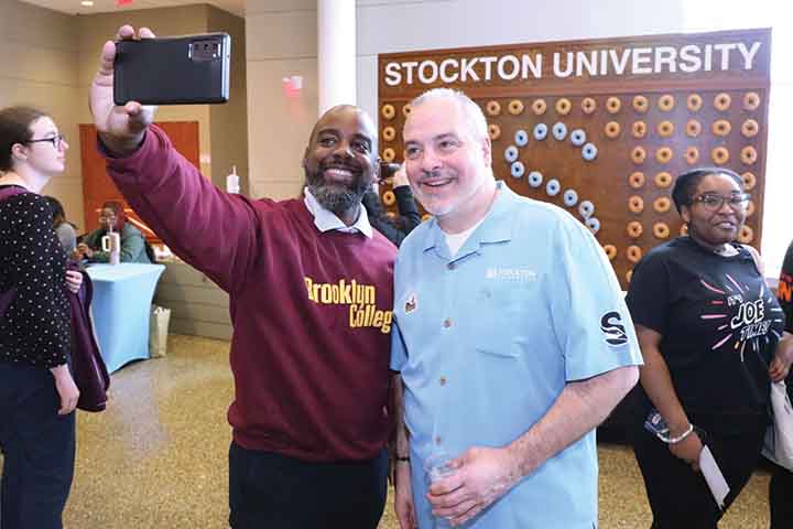 Randall Clarke in a maroon college sweatshirt and Joe Bertolino in a Stockton blue shirt in the Campus Center