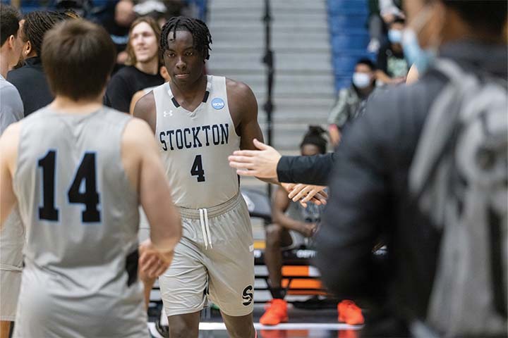 DJ Campbell in a gray Stockton uniform receives high fives from teammates