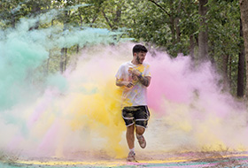 A student running through colorful clouds of powder