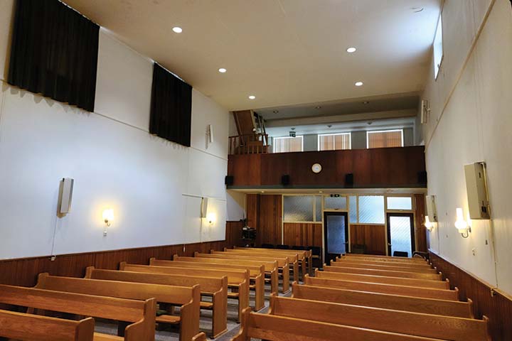 An empty church with rows of pews and a small balcony