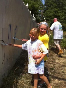 Young Emily and Kimberly Menck painting a fence