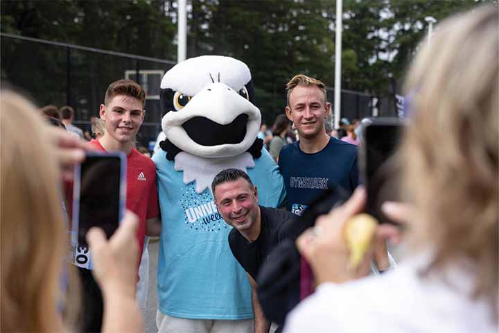 Students pose with the Talon Osprey mascot wearing a University Weekend shirt