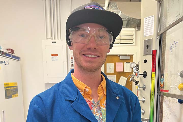 Trey Brasher in blue lab coat, safety glasses and hat