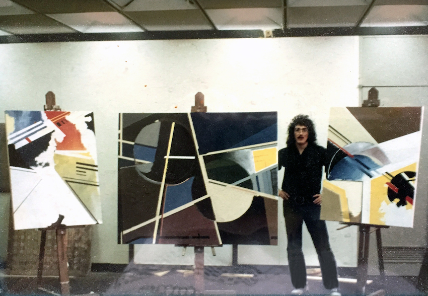 Artwork in the F-wing art studio. c. 1972-1973, Fred Sommers poses with three of his Stockton paintings. The work in the middle hung in Woody Thrombley’s office.
