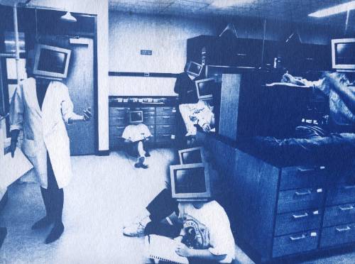 Students listening to a lecture in a lab setting with computer monitors for heads