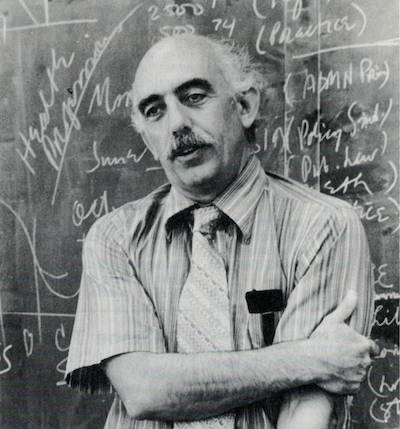 John Rickert headshot, standing in front of a chalkboard, black and white photo